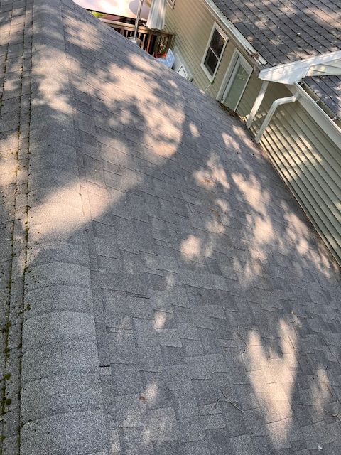 A roof with a lot of shingles on it and a house in the background.
