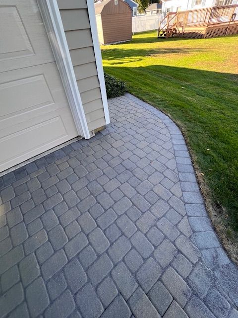 A brick walkway leading to a garage door next to a house.