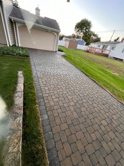 A brick walkway leading to a garage and a house.