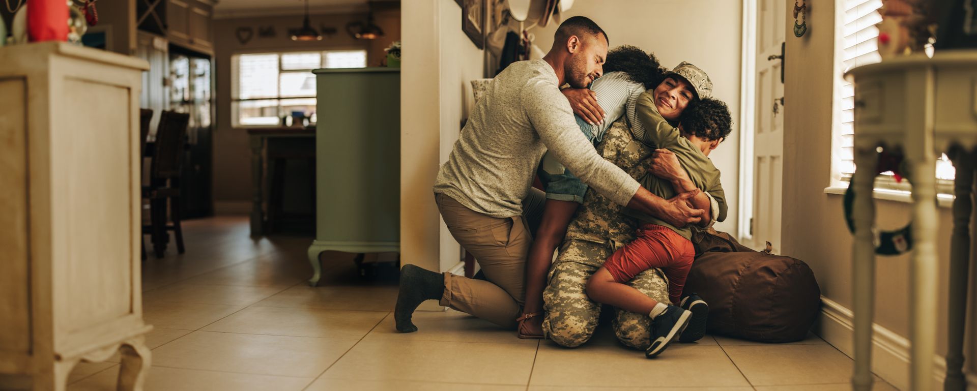 A man is kneeling down on the floor with his family.