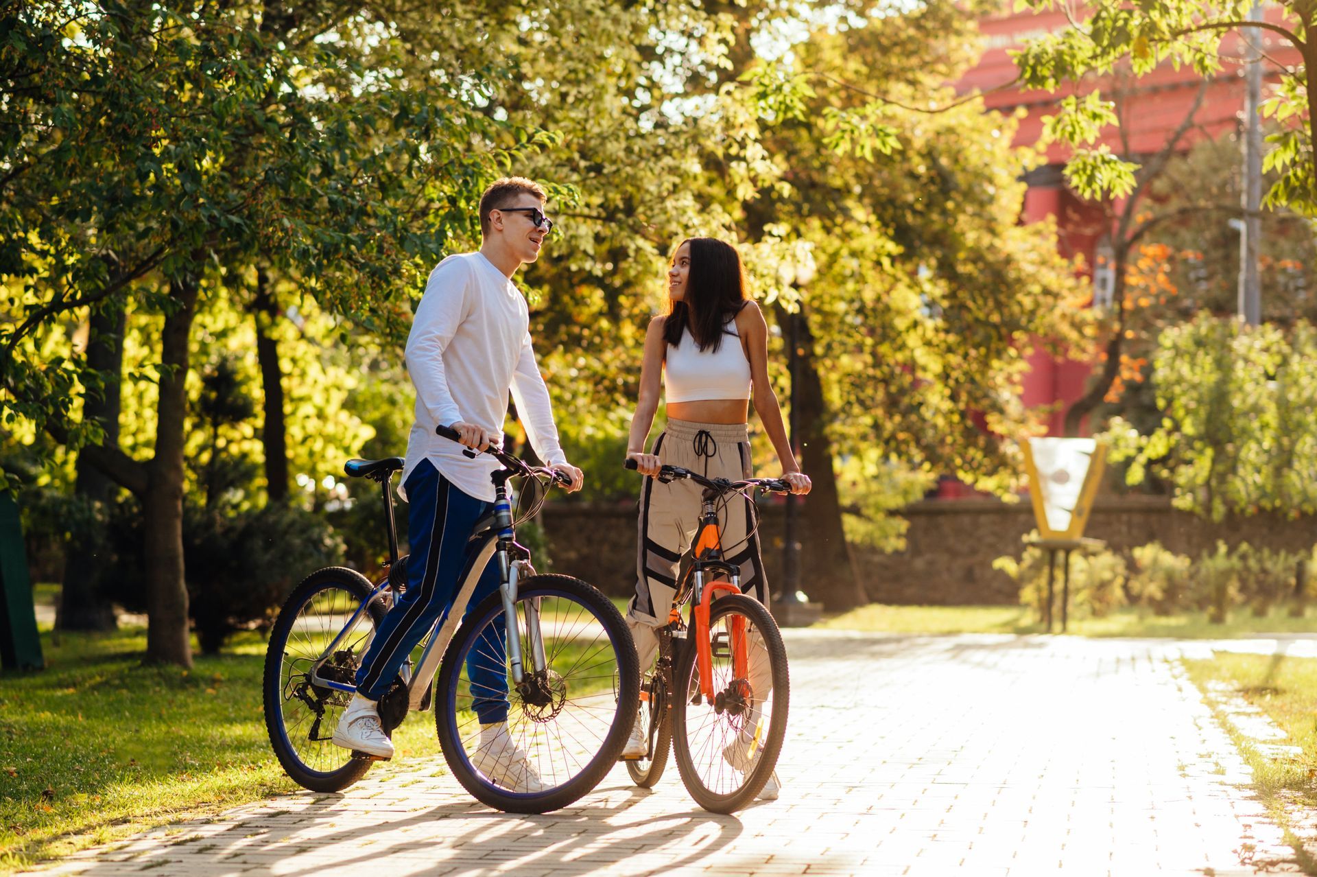A man and a woman are riding bicycles in a park.