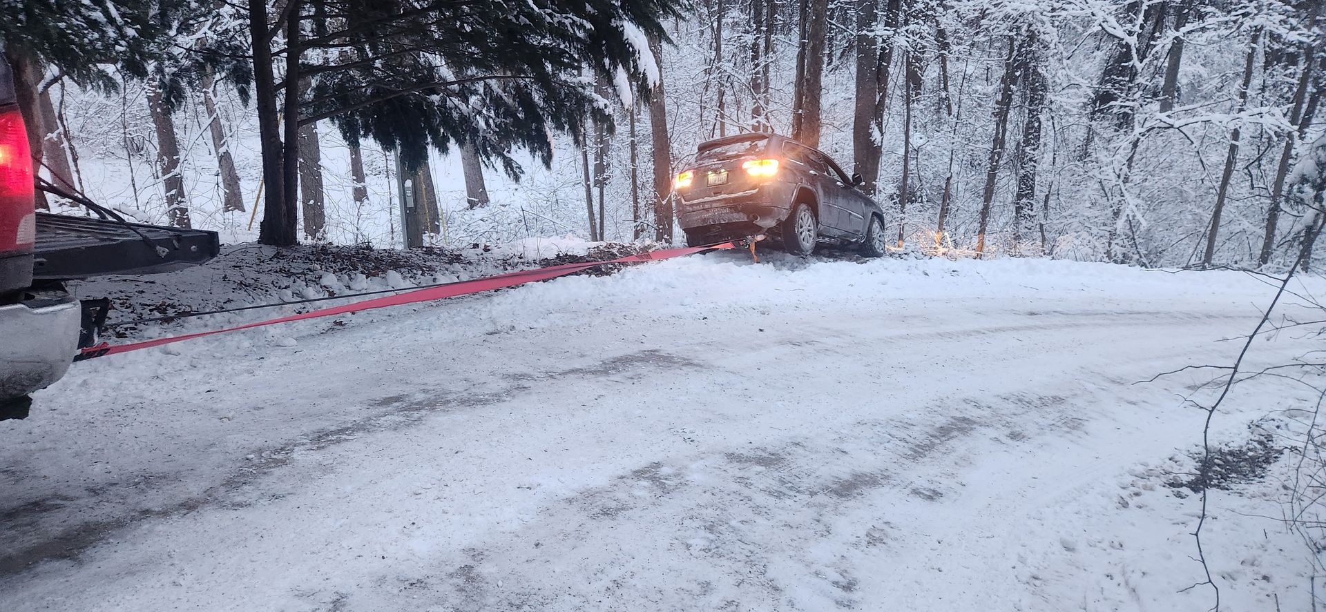 A car is driving down a snowy road in the woods.