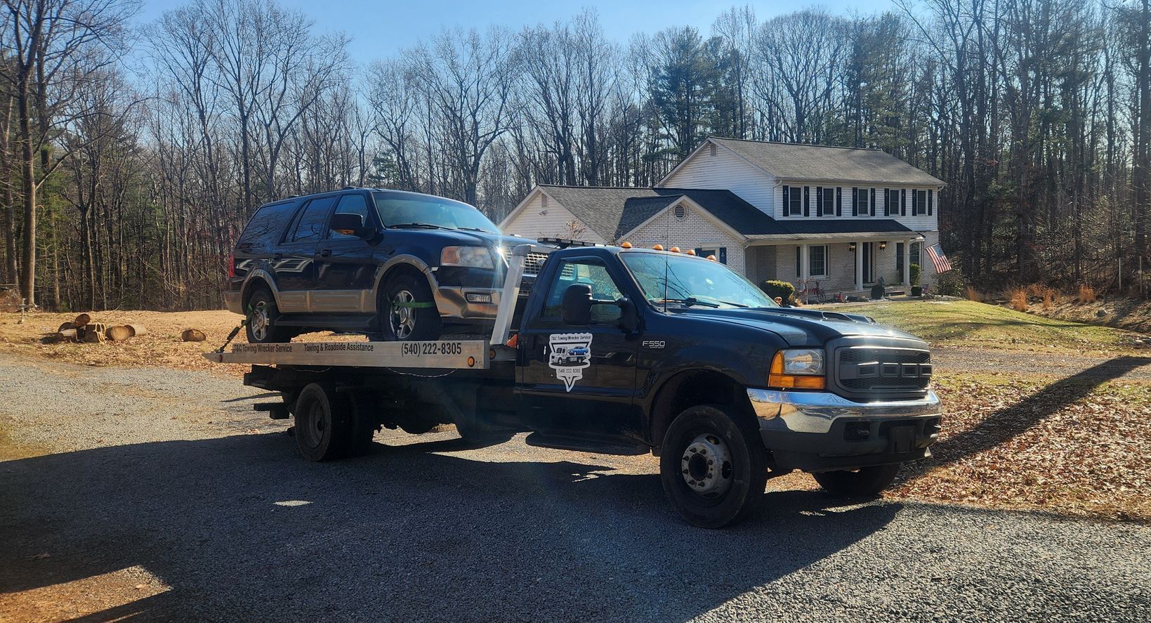 A tow truck with a suv on the back is parked in front of a house.