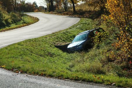 A car is stuck in the grass on the side of a road