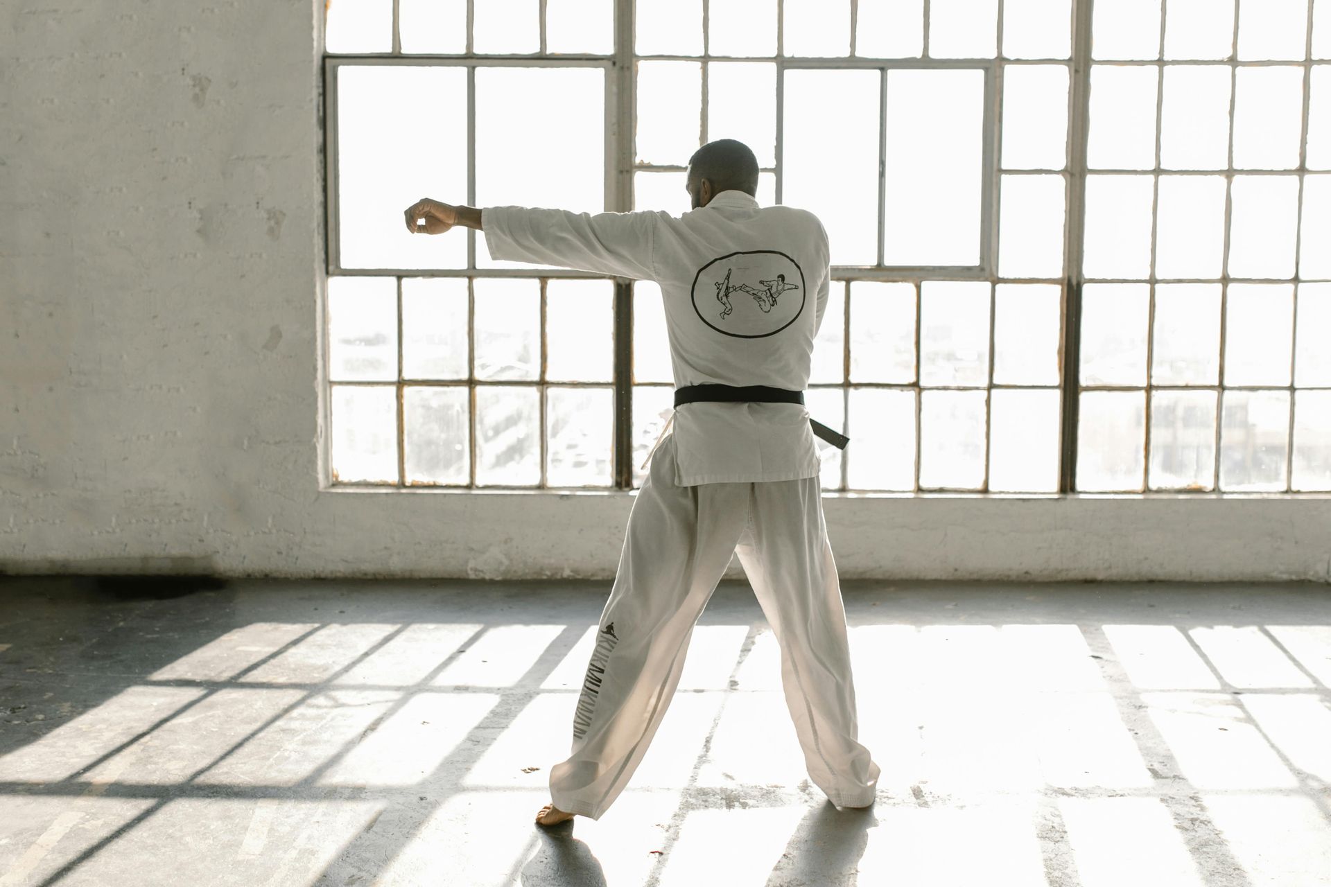 A young boy in a karate uniform is holding a helmet