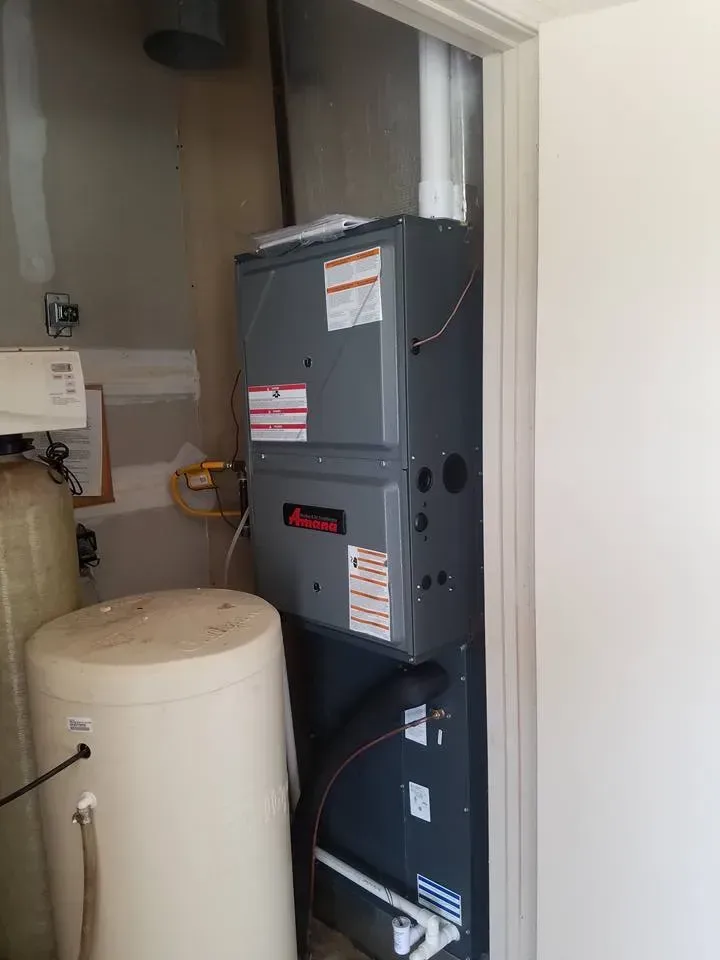 There is a water heater next to a furnace in a room.