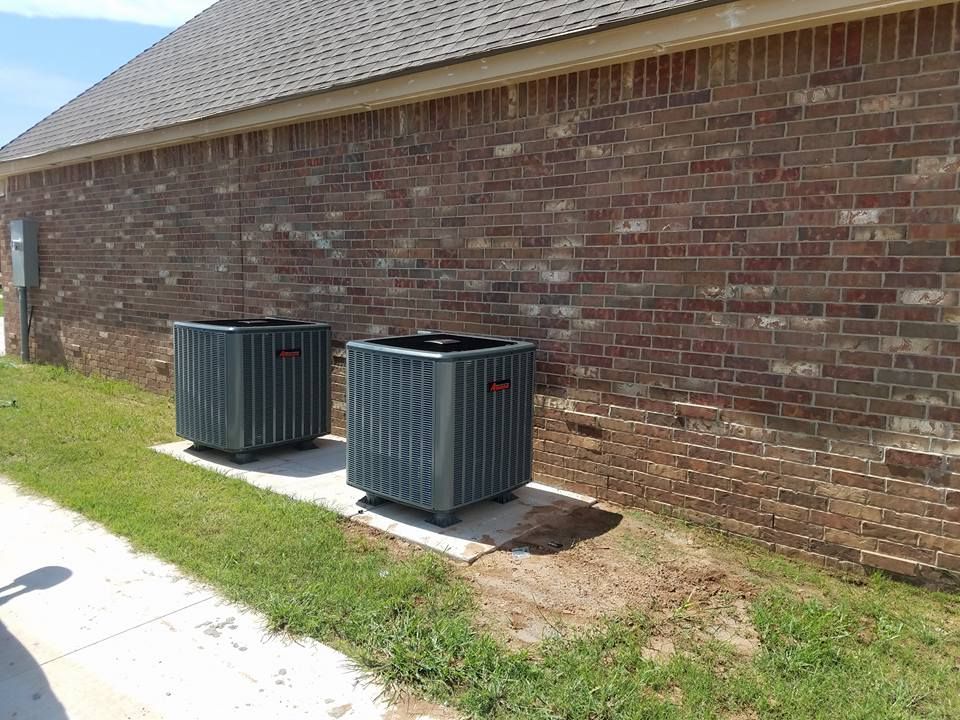 Two air conditioners are sitting on the side of a brick building.