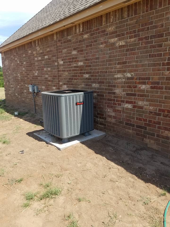 An air conditioner is sitting on the side of a brick building.