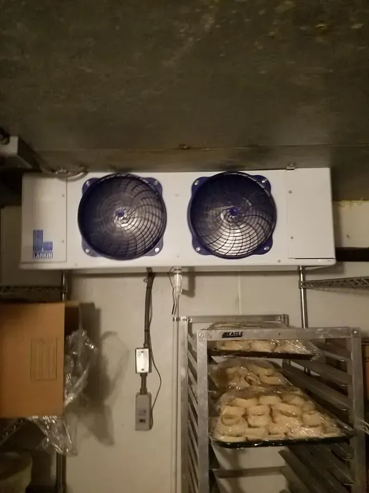 A refrigerator with two fans and a bunch of food on shelves.