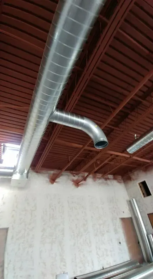 A metal pipe is hanging from the ceiling of a building.