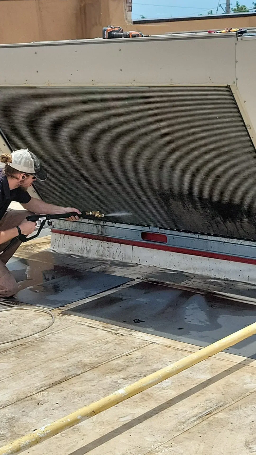 A man is working on a roof with a hose.