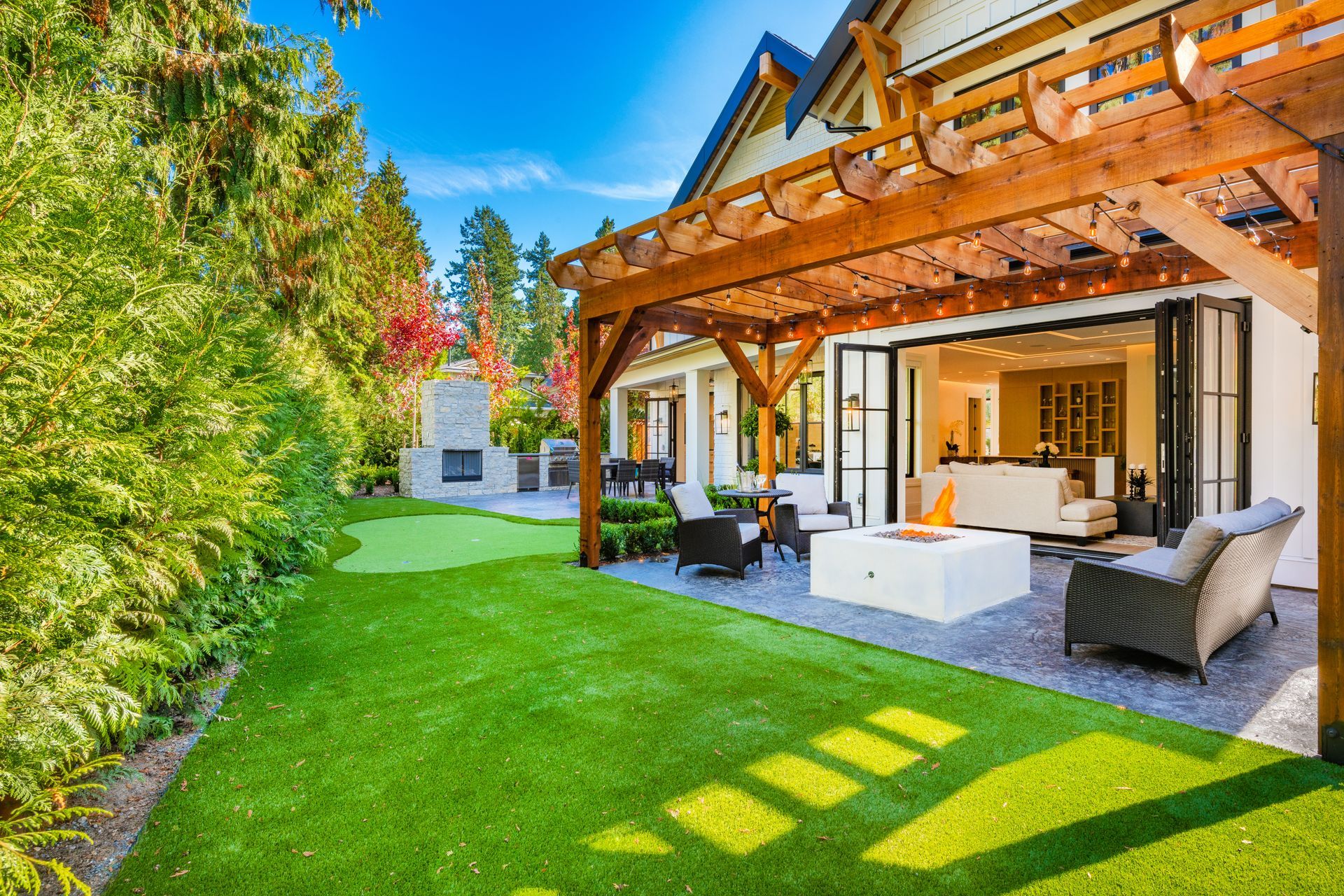 The backyard of a house with a pergola and a fire pit.