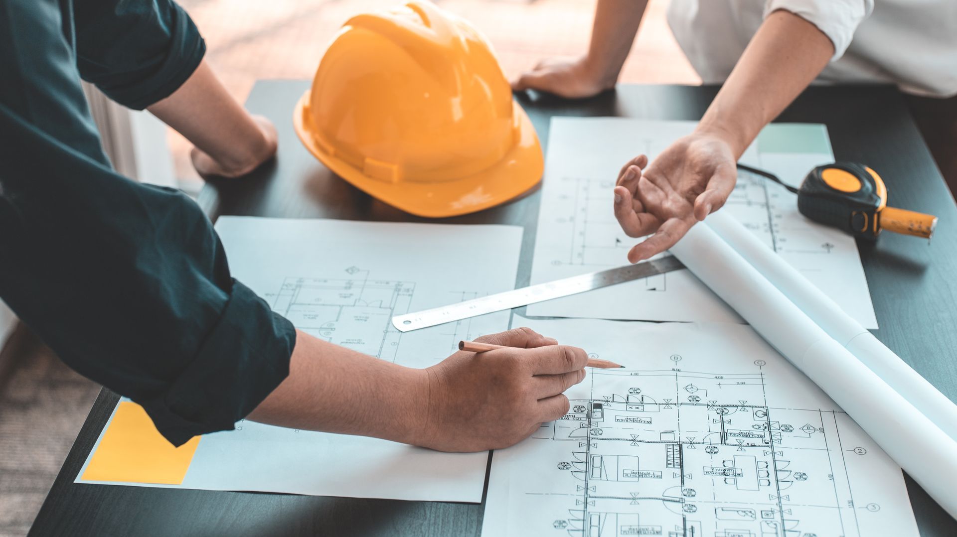 A group of people are sitting at a table looking at a blueprint.