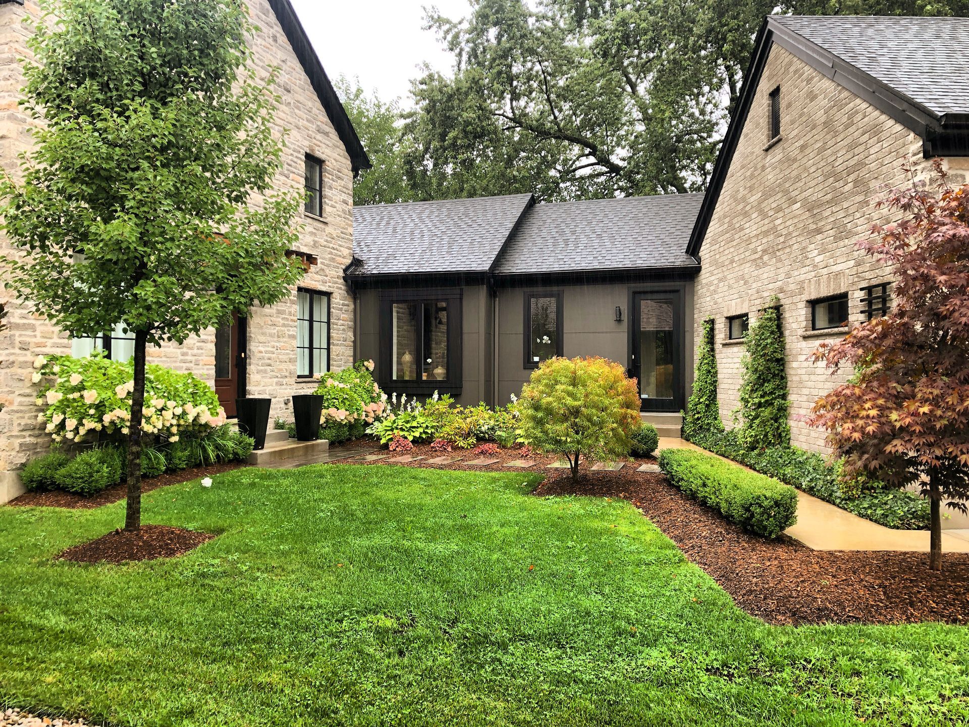 A large brick house with a lush green lawn in front of it.