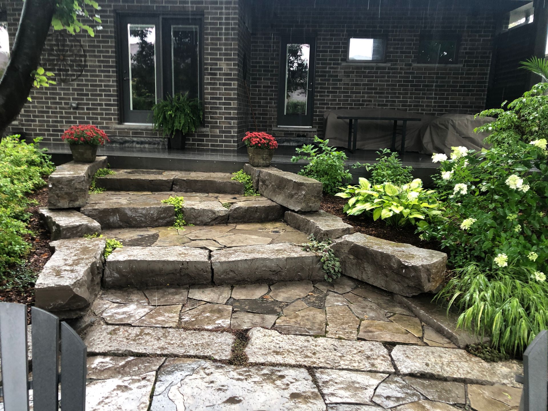 A stone patio with stairs leading up to a brick house.