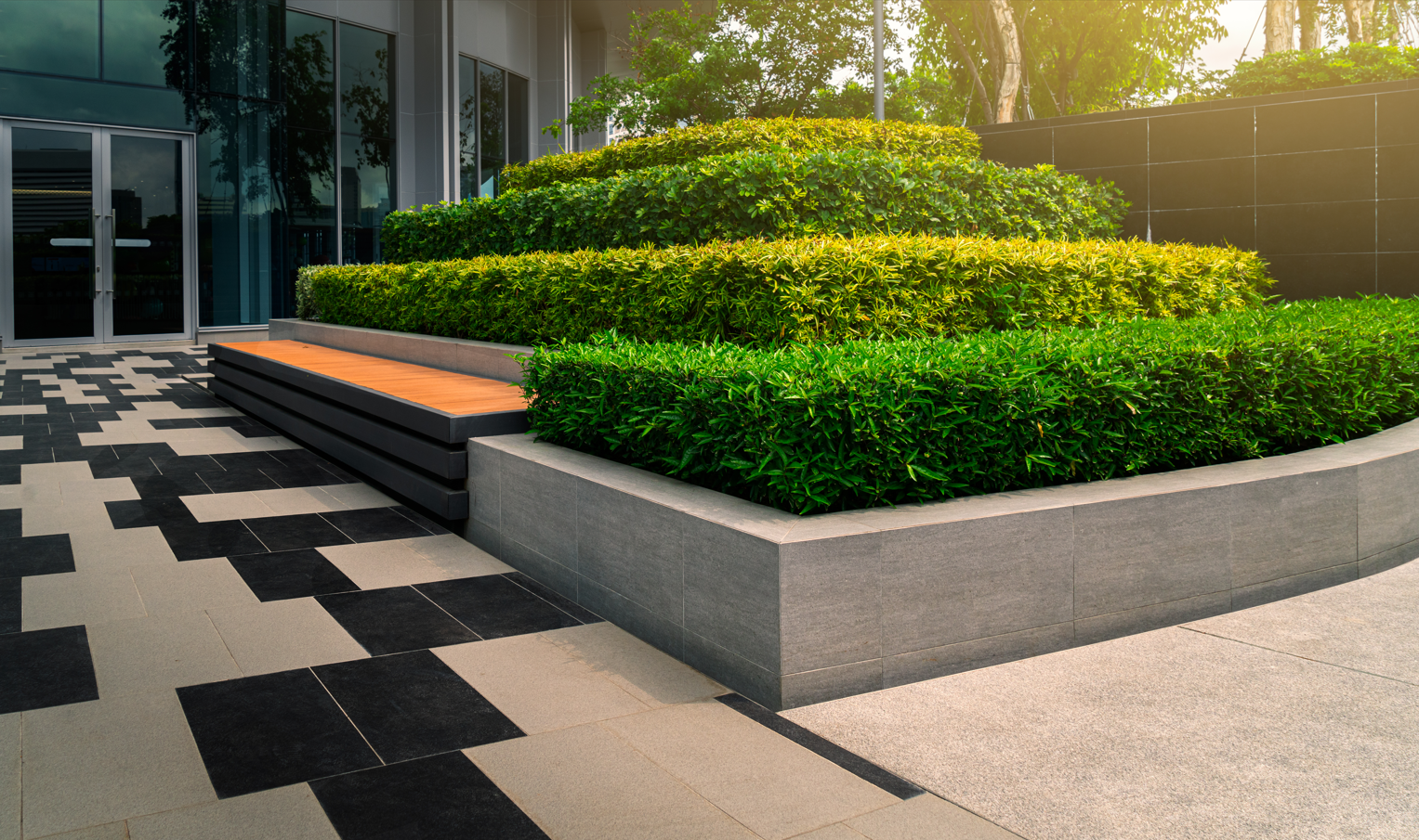 A lush green garden with a bench in front of a building.