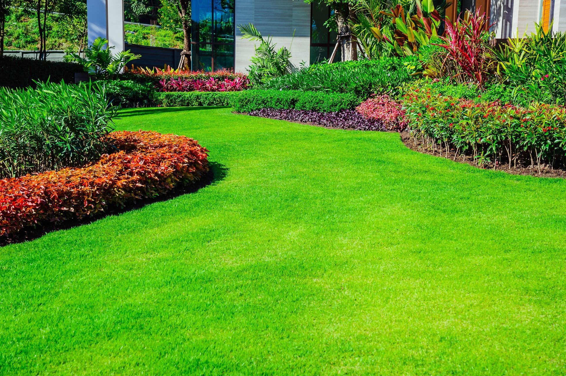 A lush green lawn with flowers and bushes in front of a house.