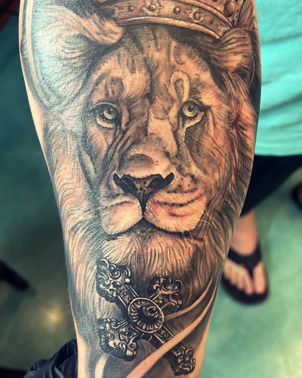 Intricate tattoo with crown and cross details on arm by Aloha Tattoo.