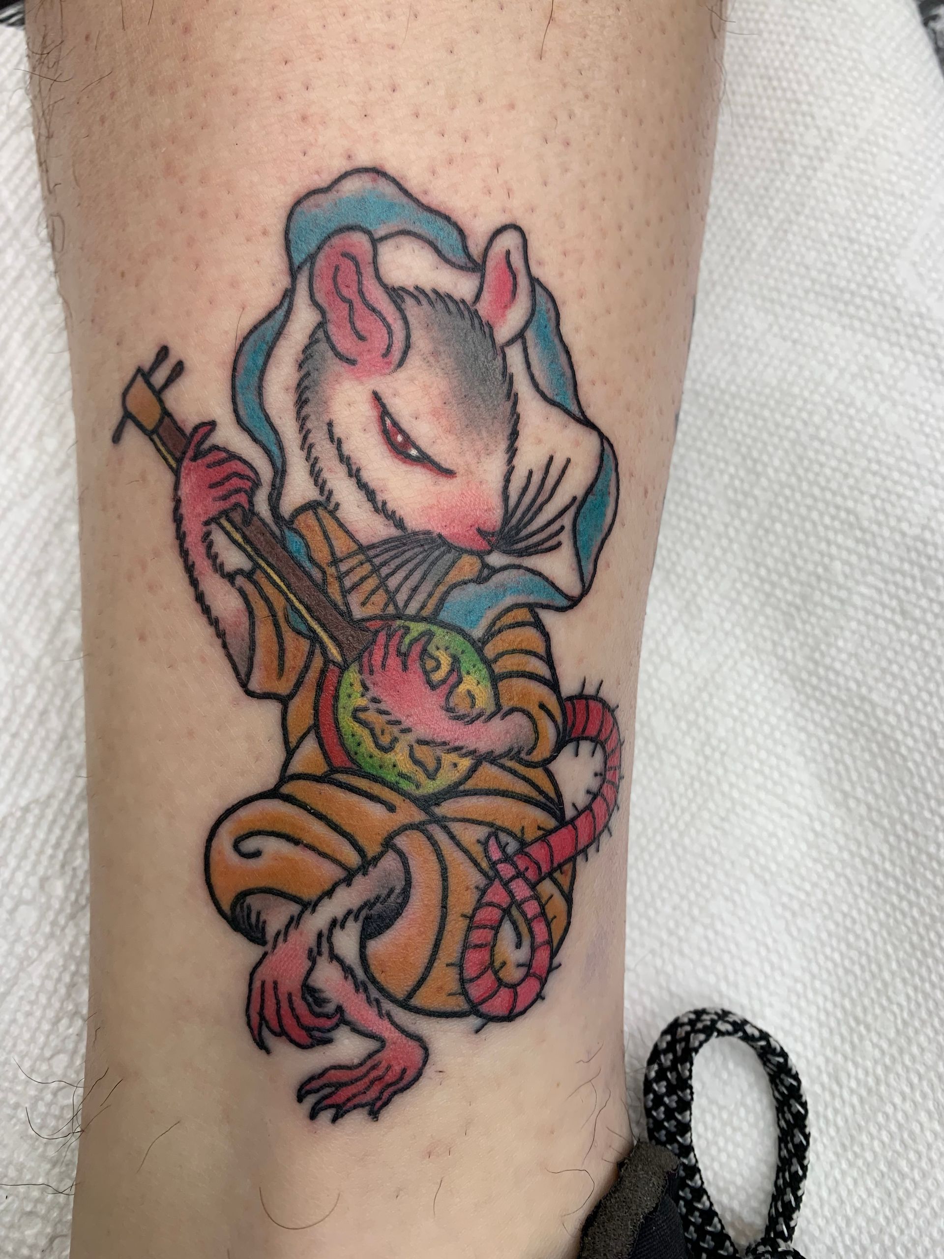 A tattoo of a rat playing a musical instrument