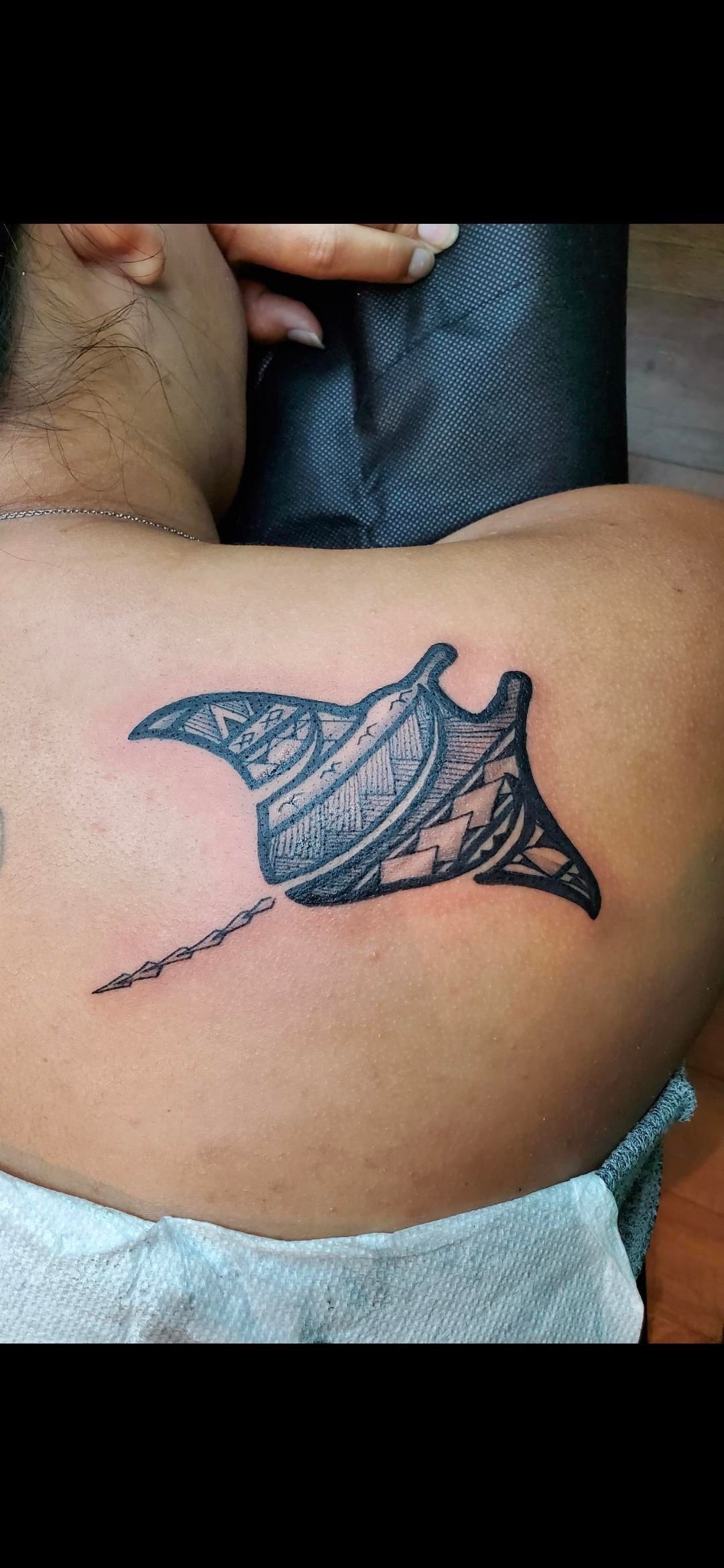 A man has a tattoo of a manta ray on his back.