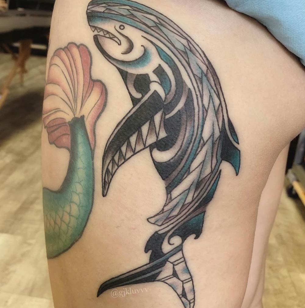 A woman has a tattoo of a shark and a mermaid on her thigh