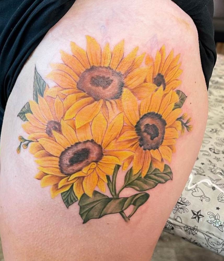 A person has a tattoo of sunflowers on their thigh.