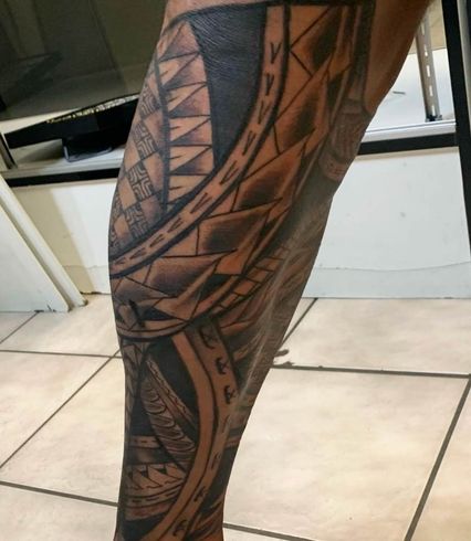 Polynesian tribal leg tattoo with bold geometric patterns and traditional black ink designs wrapping around the thigh and calf