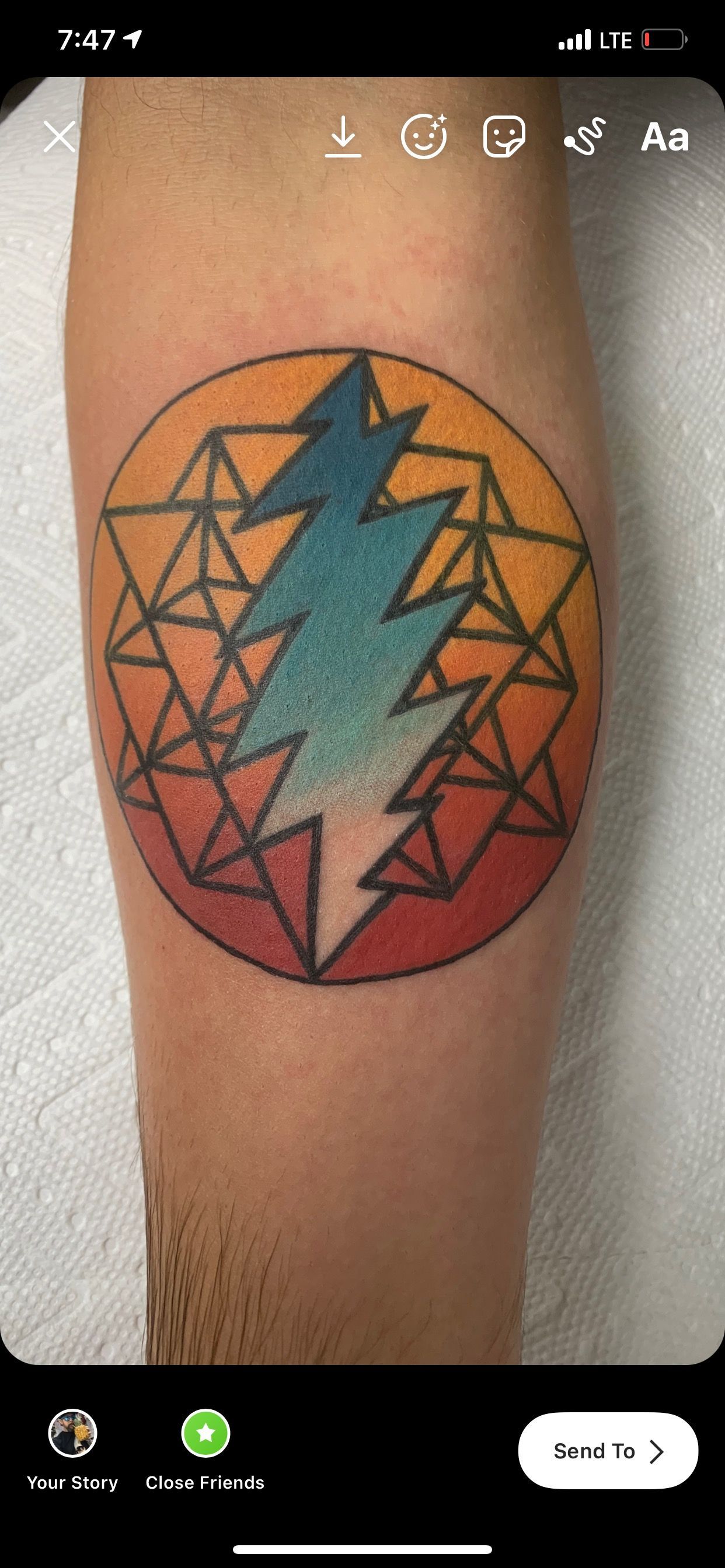 A tattoo of a lightning bolt in a circle on a person 's leg.