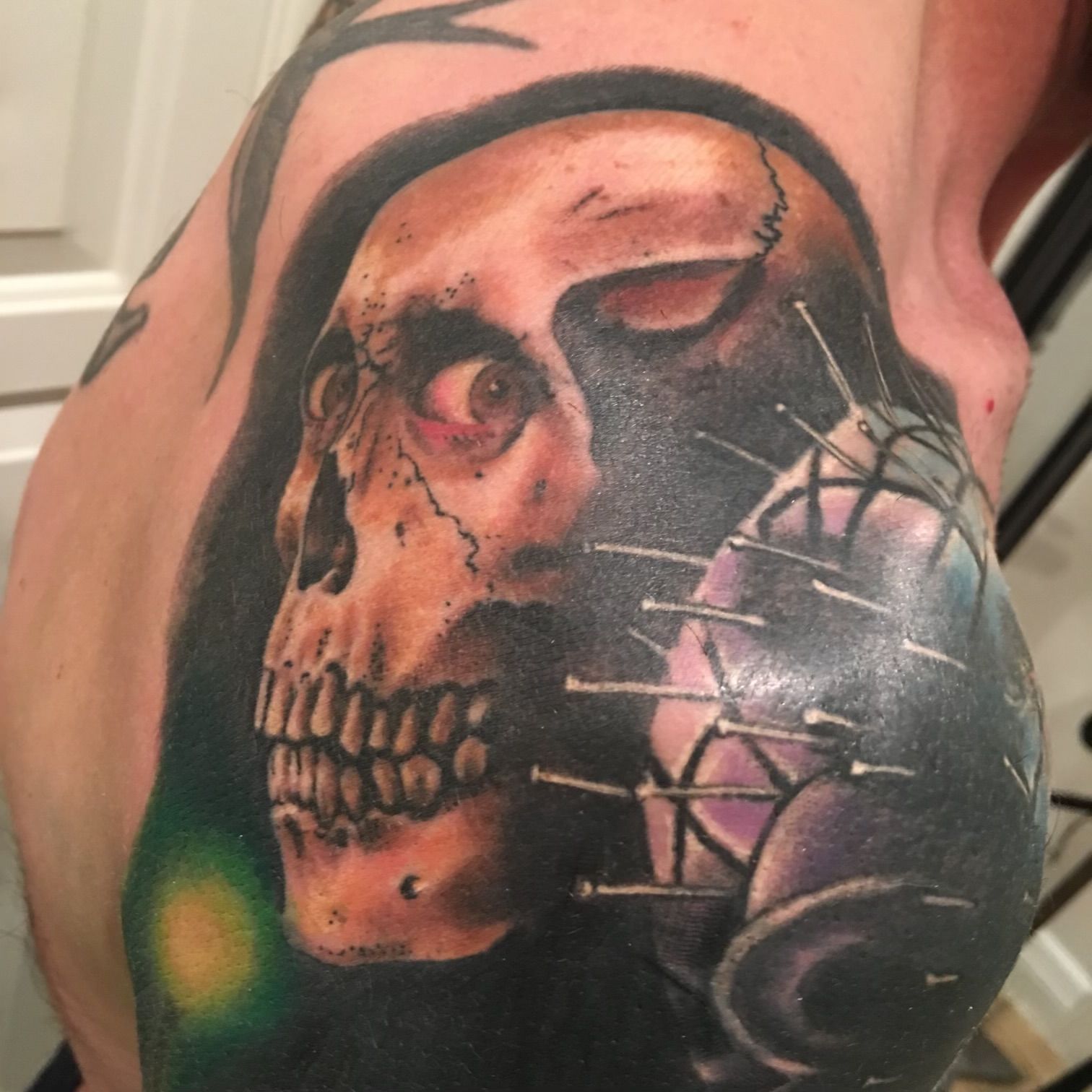 A man has a tattoo of a skull on his shoulder