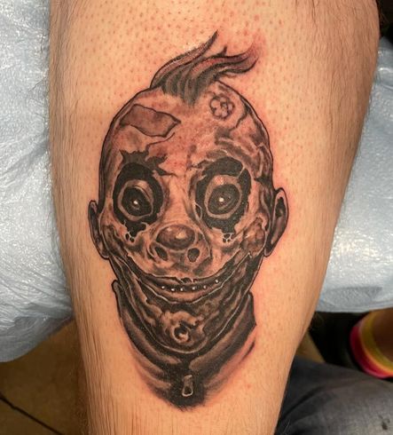 A person has a tattoo of a clown on their leg.