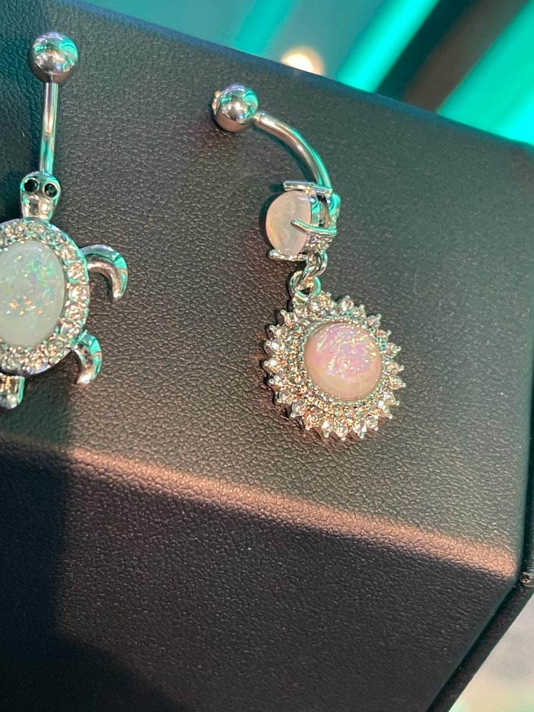 A close up of a belly button ring on a black surface.