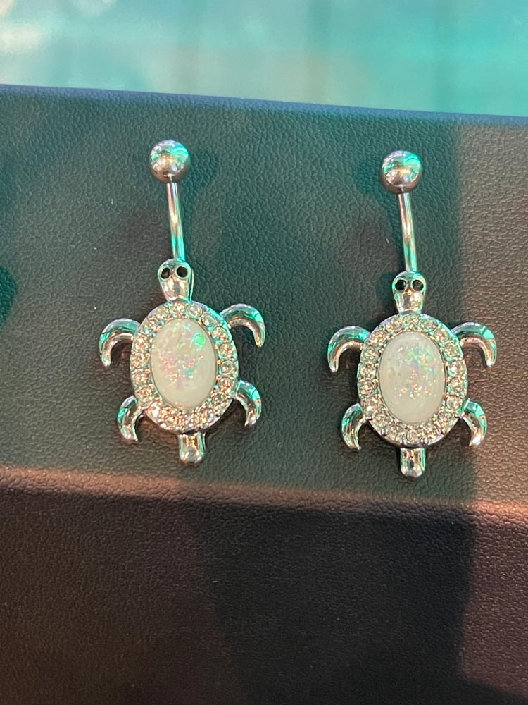 A pair of belly button rings in the shape of turtles.