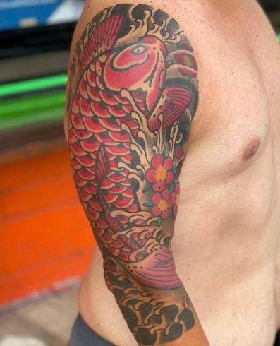 A man has a tattoo of a red fish on his arm.