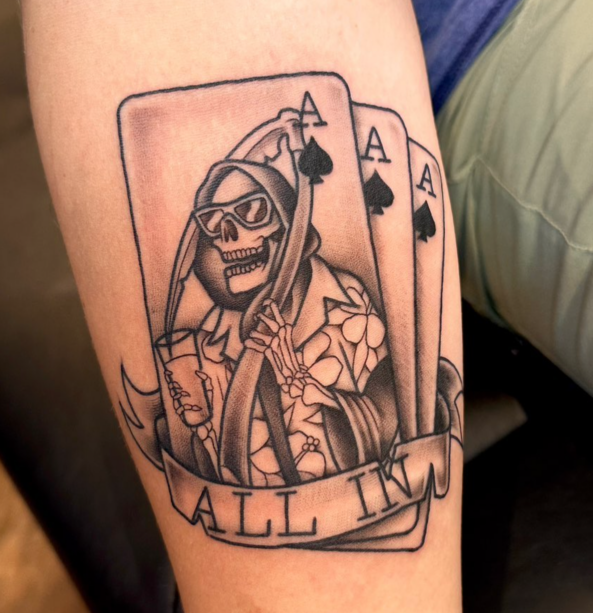 A tattoo of a grim reaper holding three aces of spades