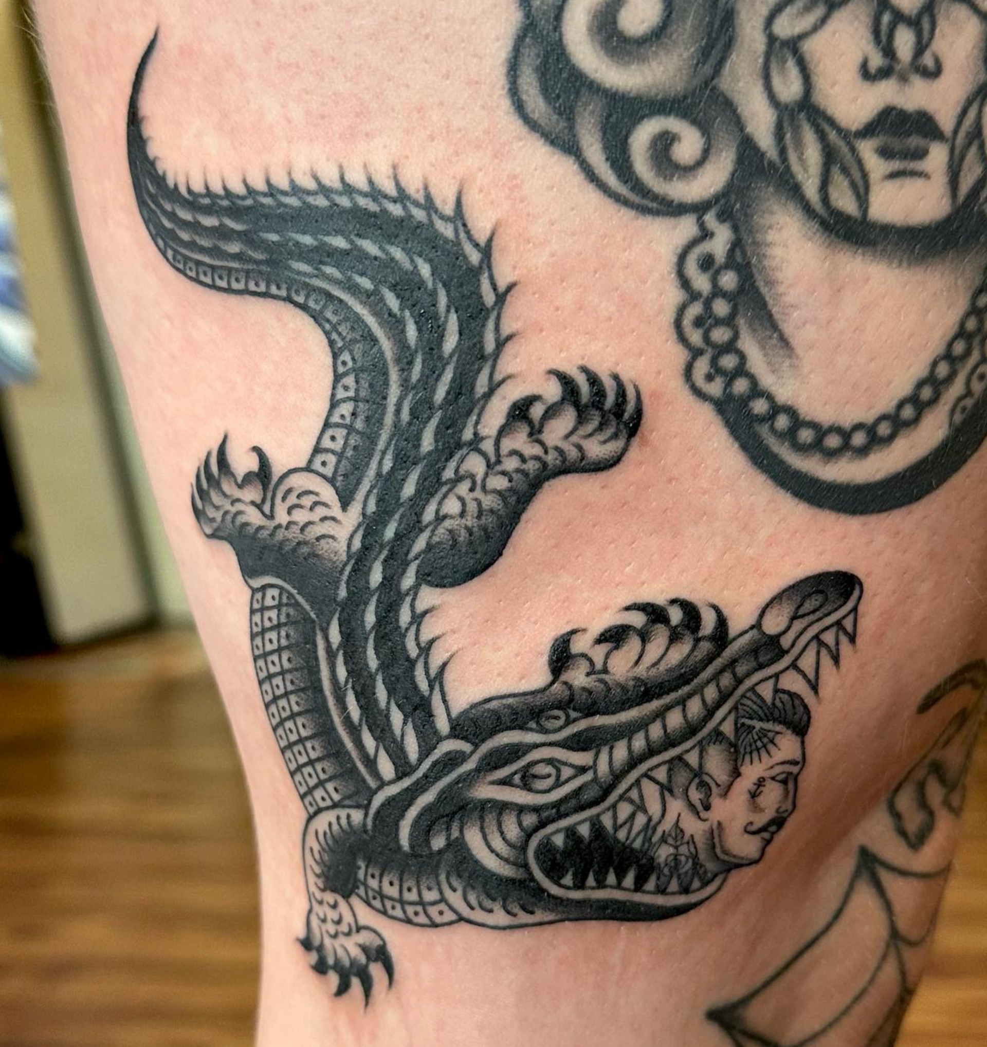 A black and white tattoo of a crocodile and a woman 's face