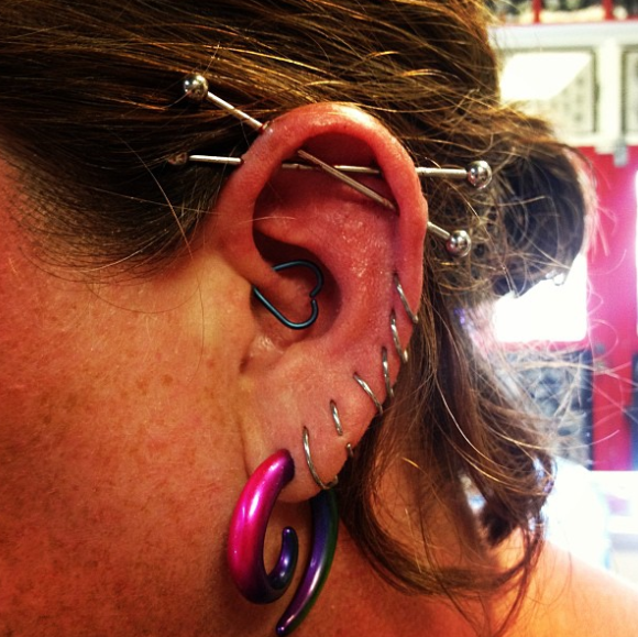 A close up of a woman 's ear with multiple piercings