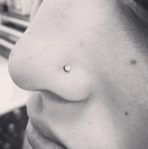 A close up of a person 's nose with a nose ring.