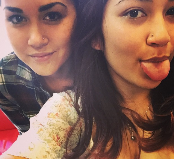 Two women are posing for a picture with one sticking her tongue out