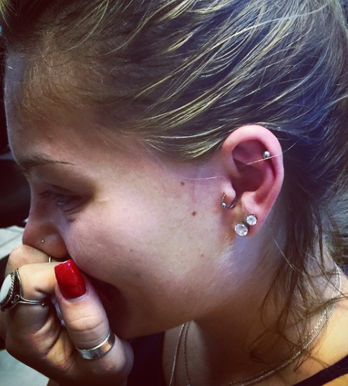 A close up of a woman 's ear with multiple piercings