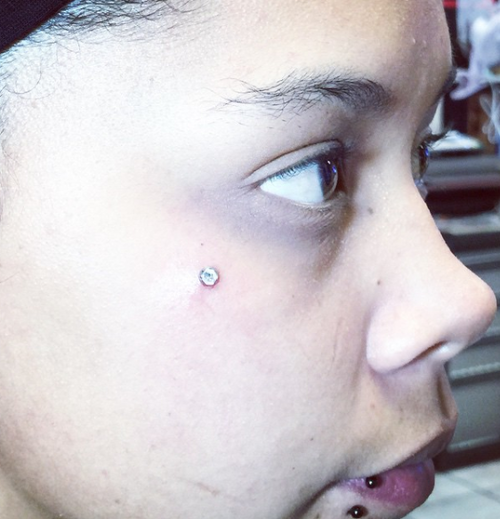 A close up of a woman 's face with multiple piercings