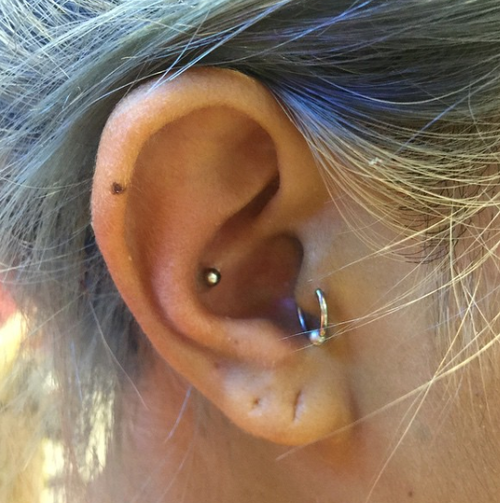 A close up of a woman 's ear with a piercing in it.