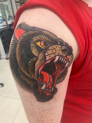 A person has a tattoo of a bear on their arm