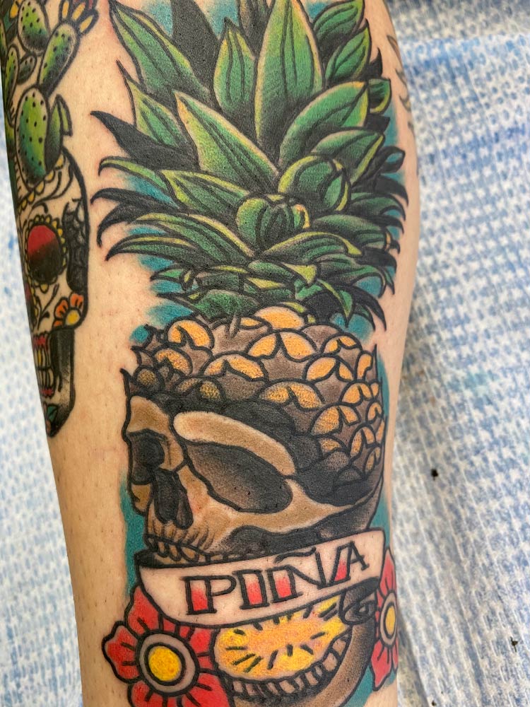 A tattoo of a pineapple in a skull with the word pina on it