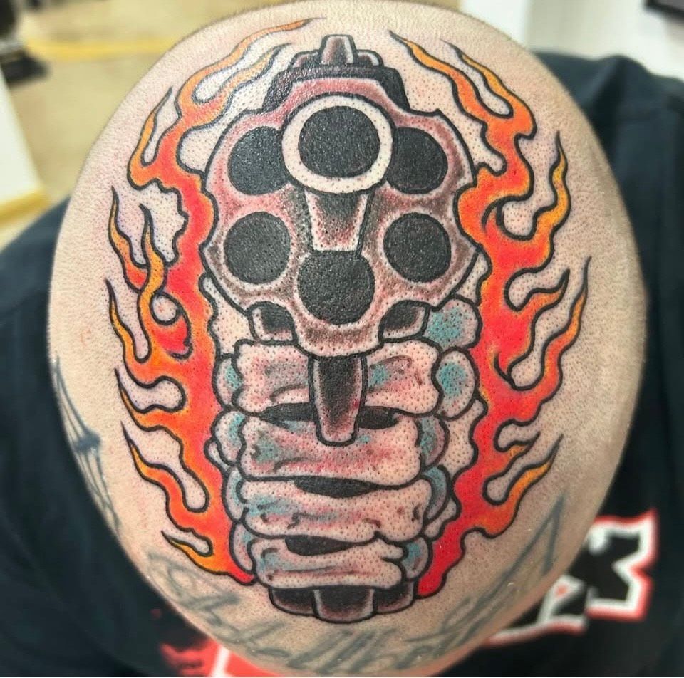 Gun and flames tattoo on a head