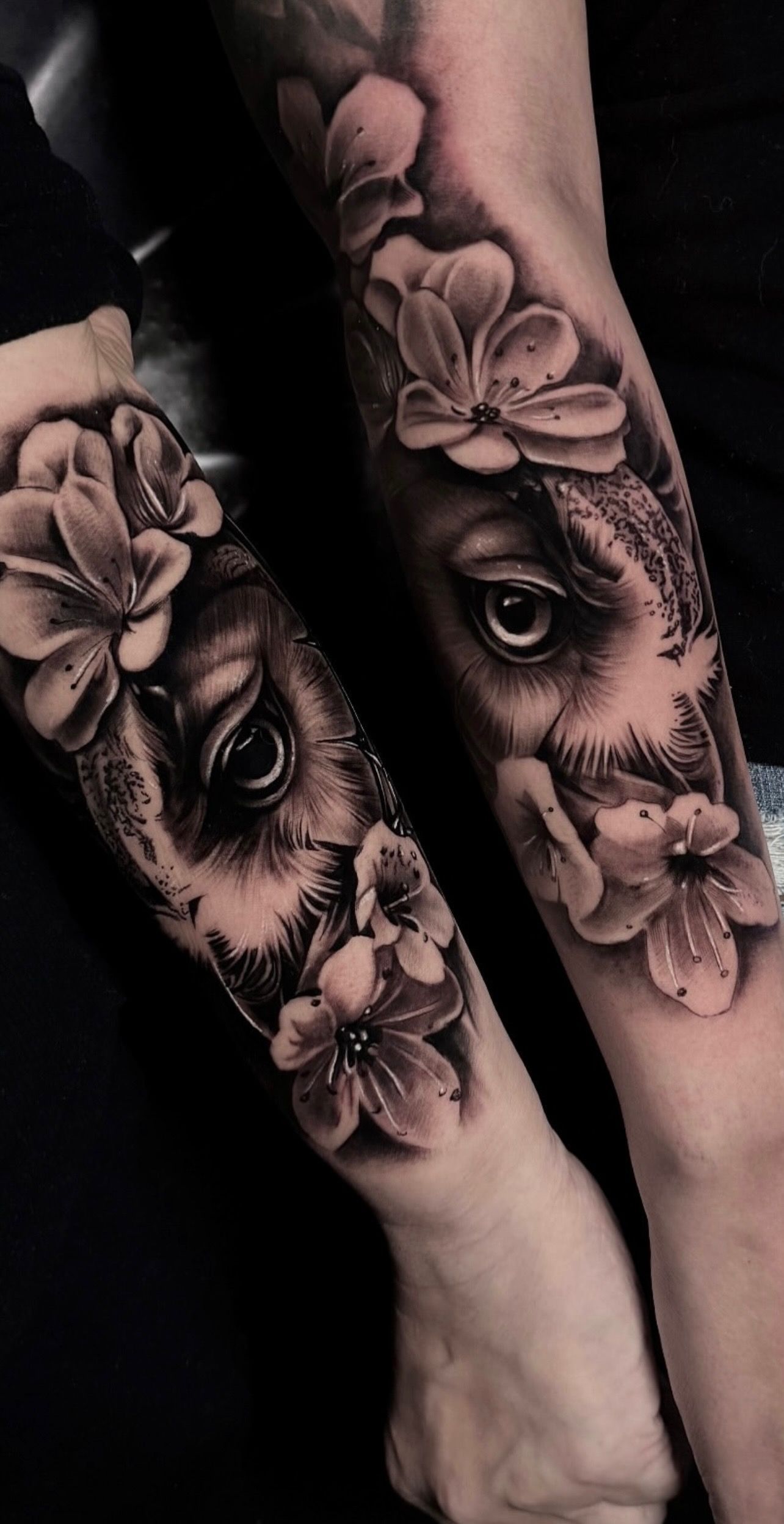 Black and white forearm tattoo featuring realistic deer eyes by Yudel