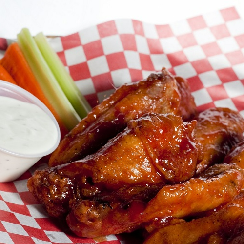 Chicken wings with celery and carrots on a checkered paper