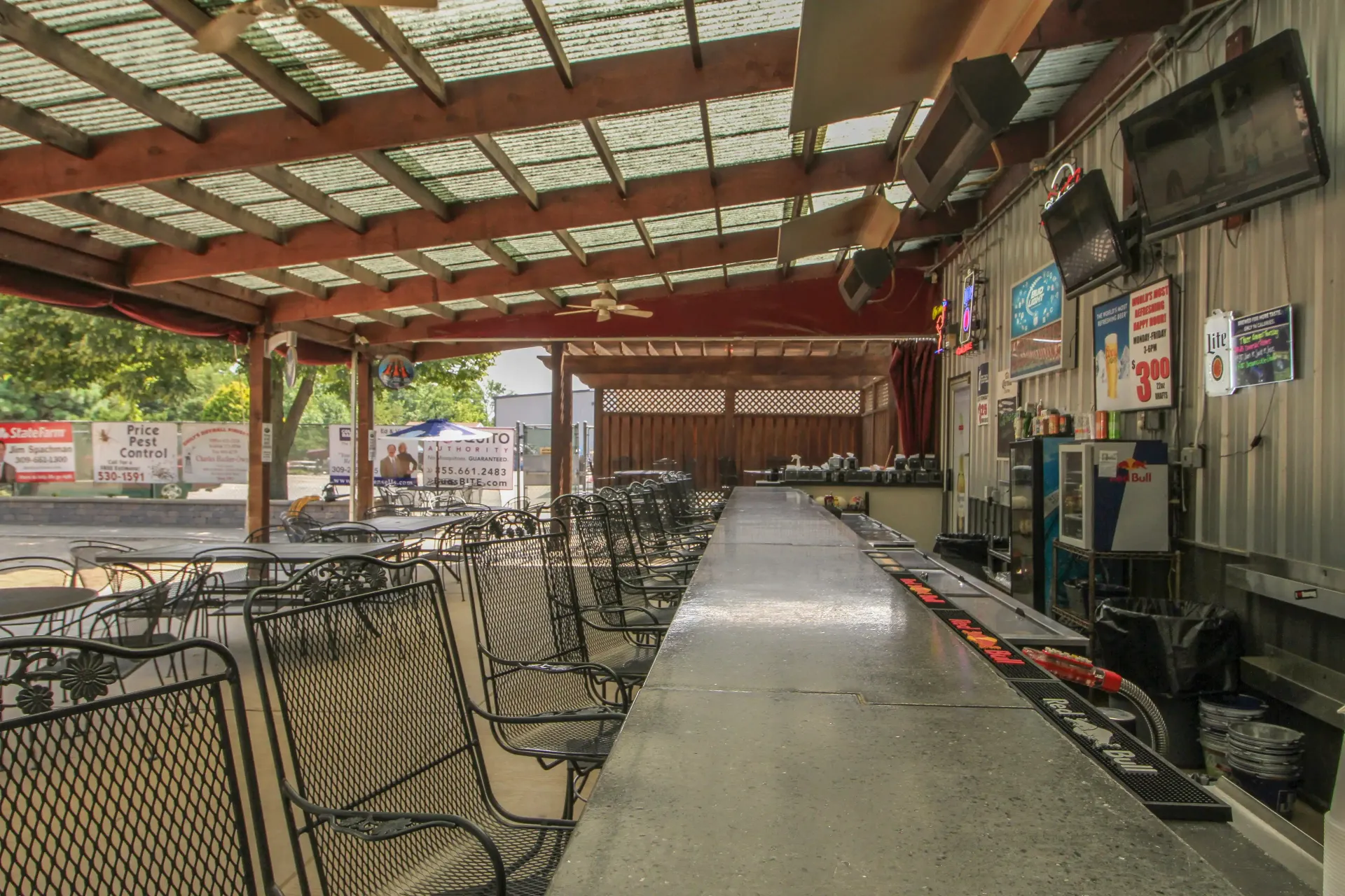 There is a long bar in the middle of a restaurant with tables and chairs.