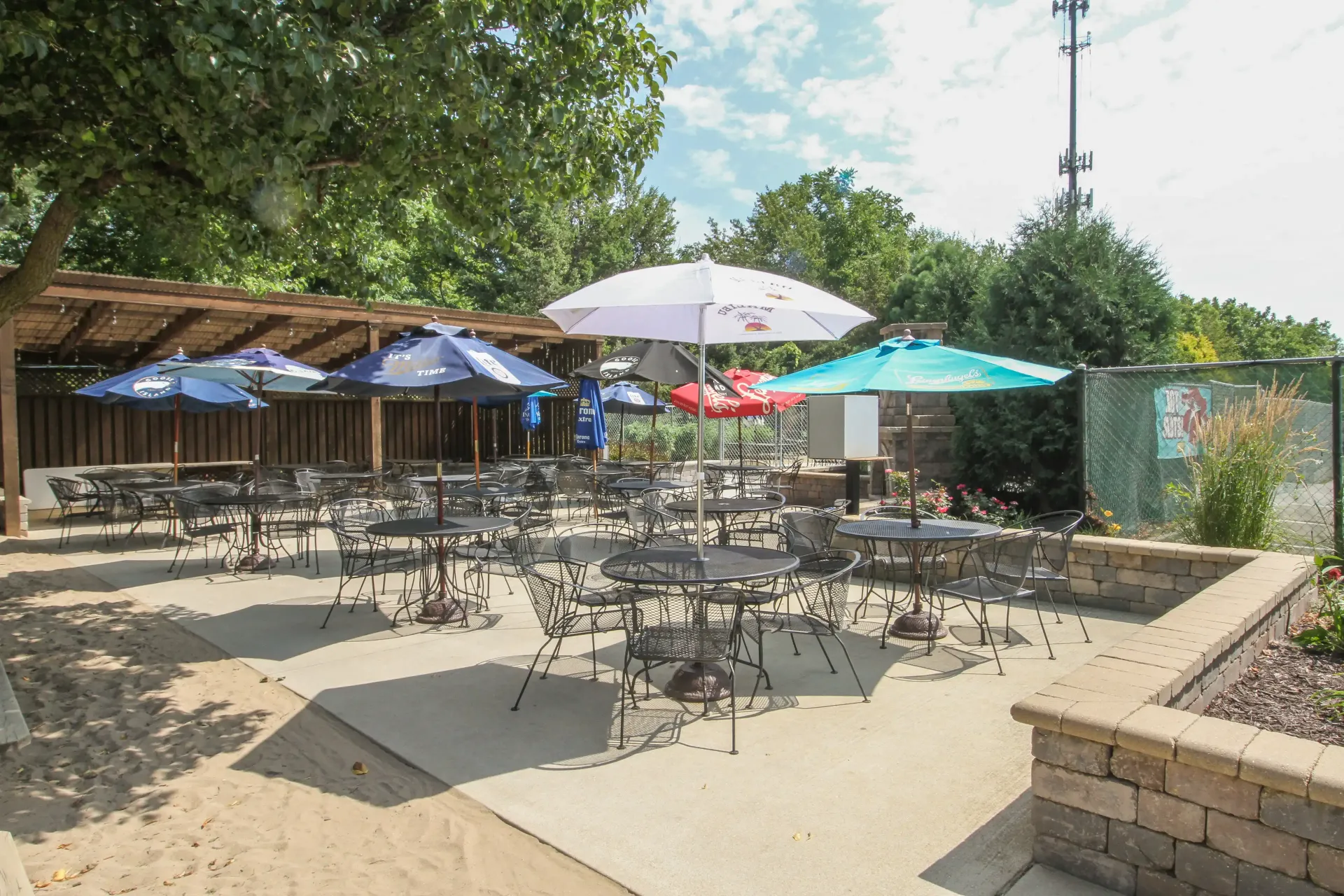 A patio with tables and chairs and umbrellas on a sunny day.