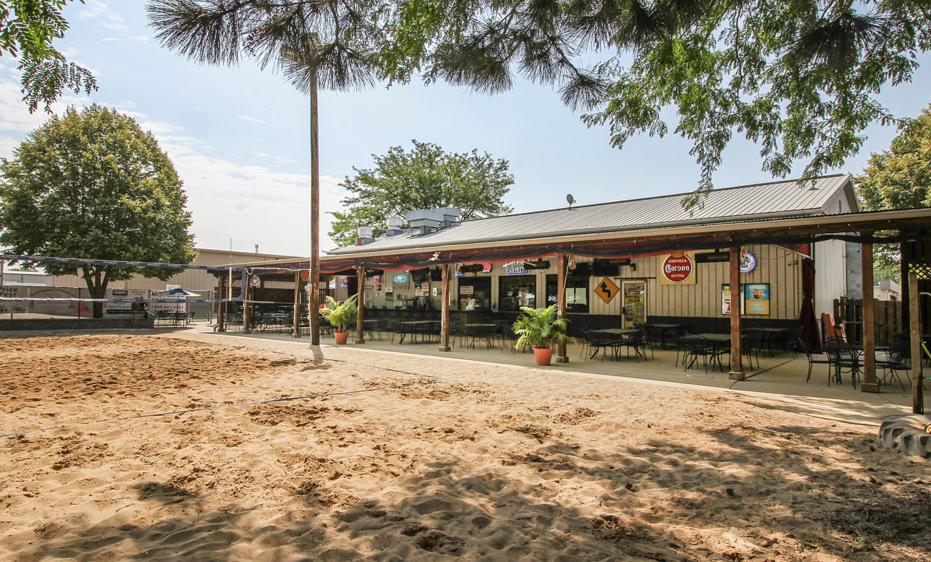 A restaurant with a large volleyball court area in front of it.