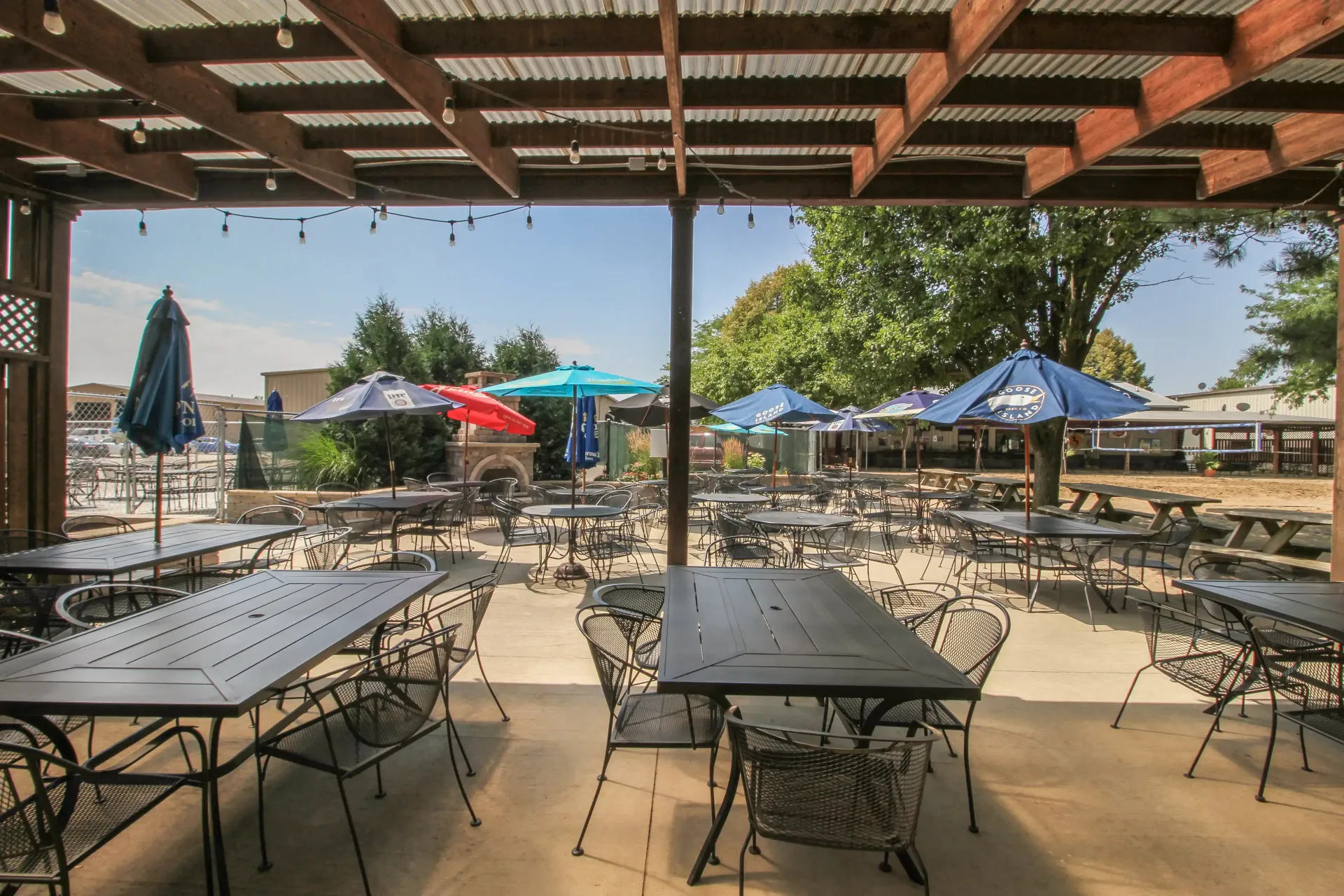 A patio with tables and chairs under a canopy with umbrellas.